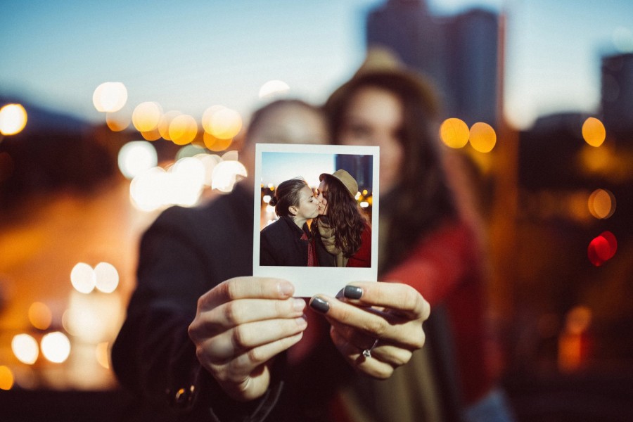 couple hold a photo of themselves kissing